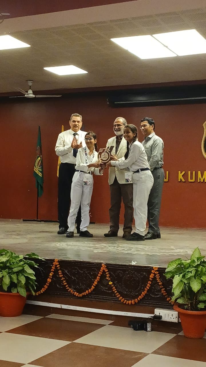 Students receiving a memento from dignitaries on a school stage