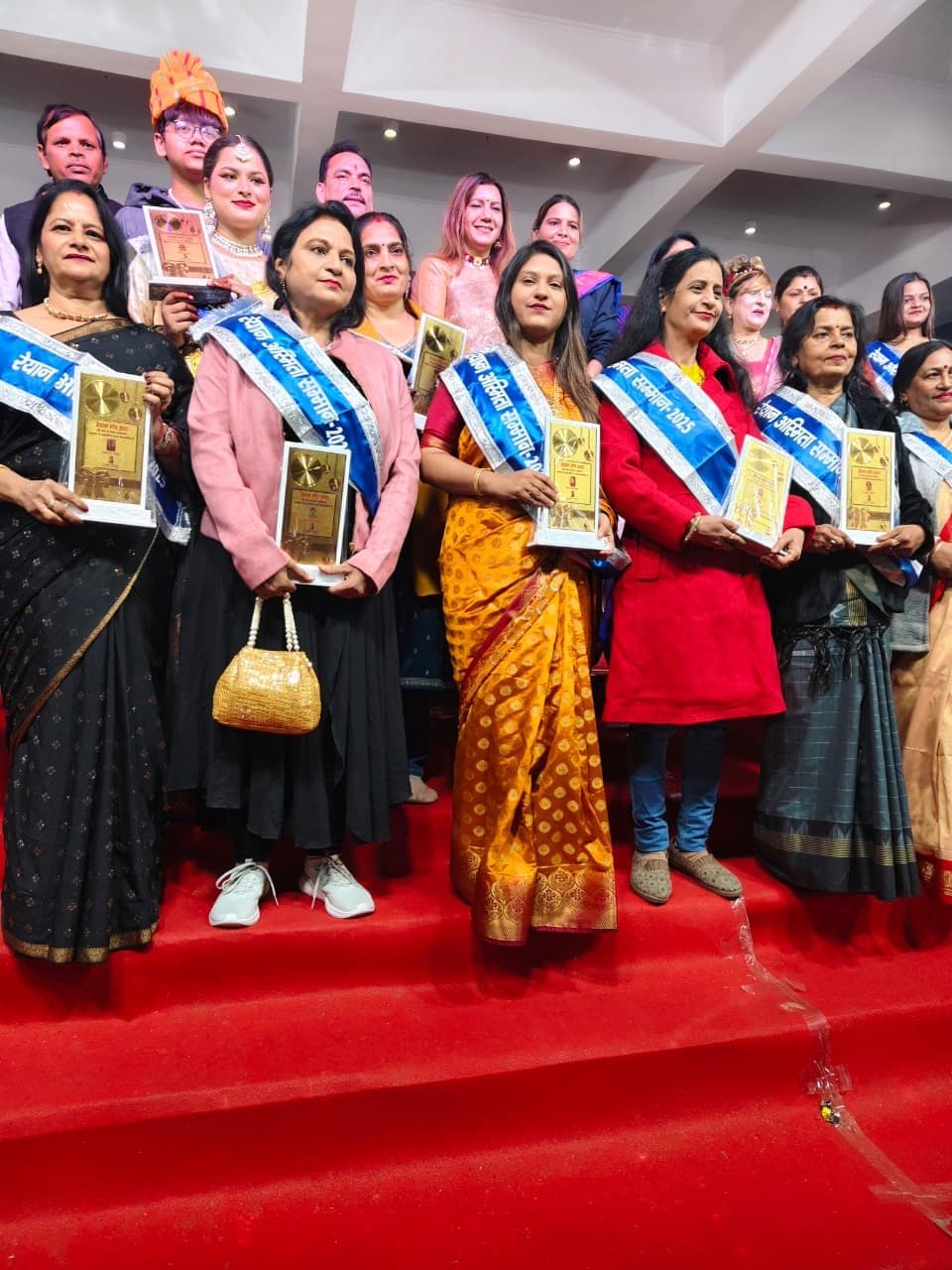 Felicitation ceremony with awardees holding mementoes and wearing sashes