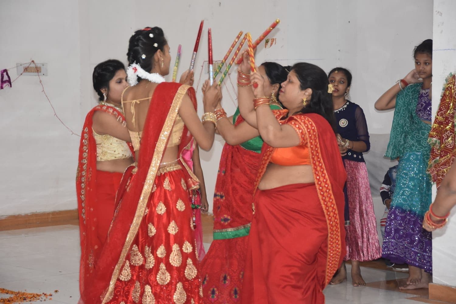 Group rehearsing a traditional sangeet choreography with dandiya sticks